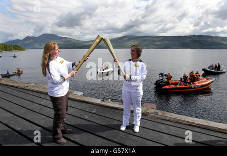 Ruth Leith, il torciere olimpico, consegna la fiamma olimpica a Sheila McNeil (a sinistra) nel villaggio di Luss, sulle rive del Loch Lomond. Foto Stock