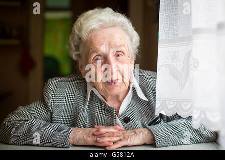 Ritratto di una donna anziana seduta al tavolo. Foto Stock