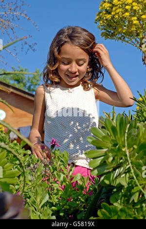 Carino il brasiliano sei anno vecchia ragazza tenendo un fiore in natura, Ibiza, Spagna Foto Stock