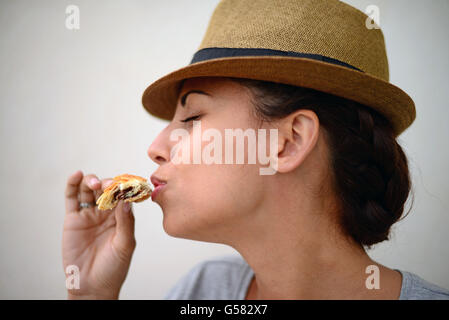 Giovane donna di mangiare croissant al cioccolato in strada Foto Stock