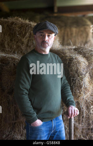 L'uomo avente una pausa veloce da mucking fuori una stabile. Foto Stock