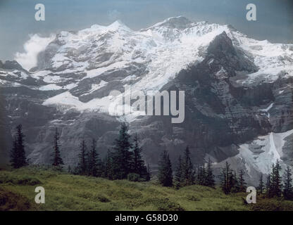 Der Hauptreiz der Aussicht, die sich hier auftut, liegt in der unmittelbaren Nähe der Jungfrau, die in ihrer sinnberückenden Schönheit den Blick vollständig gefangen nimmt. Die klare Alpenluft rückt uns die einzelnen pièces così deutlich vor Augen, dass wir sie trotz der Verhältnisse riesenhaften, die uns über die Entfernung hinwegtäuschen, durch einen Büchsenschuß zu erreichen vermeinen. Erhabene Als Königin steigt sie aus dem Trümletental in einem Felsenfundament hervor, über das wie ein Mantel die weißen Firnfelder und Gletscher gebreitet sind, welche mit ihren Abstürzen und Spalten den Faltenw Foto Stock