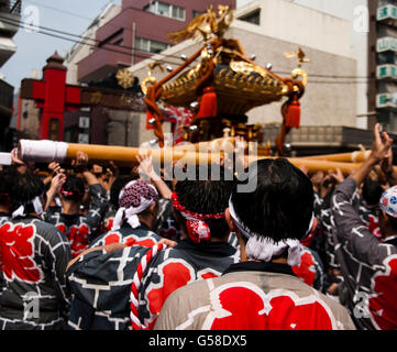 Uomo Orologi altri uomini che trasportano un santuario portatile presso il Tokyo Fukugawa Hachiman festival Foto Stock