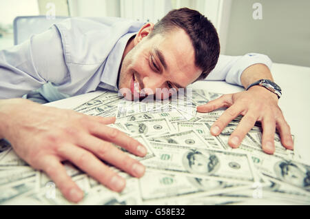 Happy businessman con il mucchio di soldi in ufficio Foto Stock