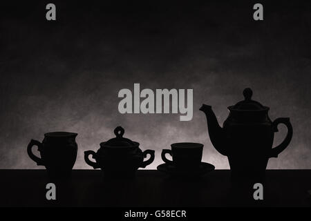 Sagome scure di ware per il caffè su un gradiente di sfondo non uniforme Foto Stock