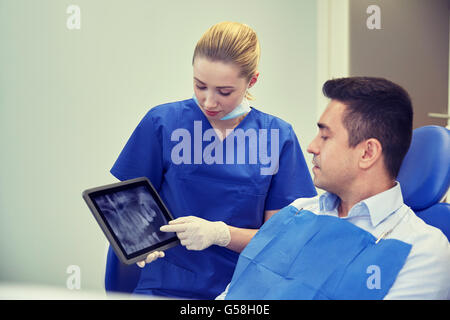 Dentista femmina con tablet pc e paziente di sesso maschile Foto Stock