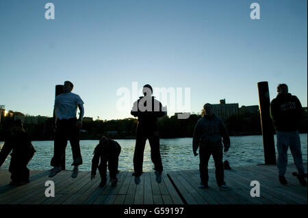 I soci del Club jump per rilassare i muscoli dopo la mattina presto pratica sessione sul fiume di Harlem, a New York City, 11 novembre 2004 Foto Stock