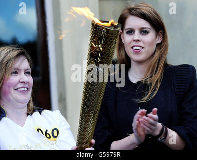 La principessa Beatrice (a destra) accoglie Janet Baker, portatore di torcia, e la fiamma olimpica sui gradini di Harewood House, vicino a Leeds, durante l'Olympic Torch Relay. Foto Stock