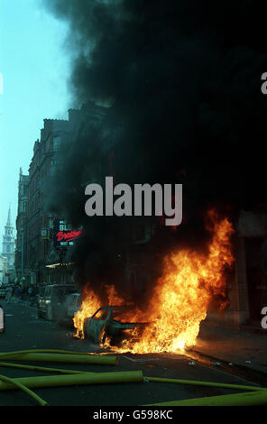 Un'auto in fiamme a St. Martin's Lane, nel centro di Londra, in seguito alla violenza scoppiata dopo una protesta a Trafalgar Square contro la cosiddetta tassa sul sondaggio si è sviluppata in una sommossa. Foto Stock