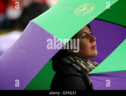 Un fan del Tennis si rifuga dalla pioggia sul Monte Murray durante il settimo giorno dei Campionati di Wimbledon 2012 all'All England Lawn Tennis Club, Wimbledon. Foto Stock