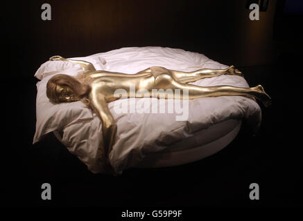 Un modello di Shirley Eaton come famosa Bond girl Jill Masterson dipinse oro dal film Goldfinger (1964) ai cinquanta anni di vista stampa stile Bond al Barbican, Londra. Foto Stock