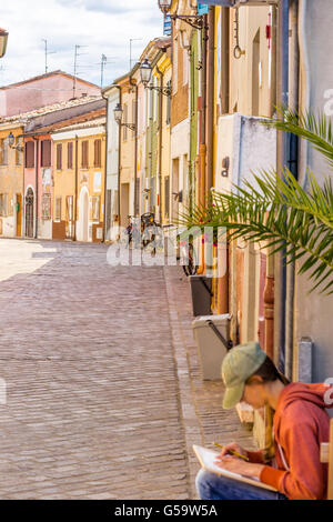 L'allegro case vivacemente colorate di pesca un affascinante villaggio in Romagna, Italia con ragazza di disegno Foto Stock