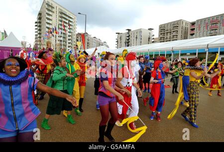 La vista che saluta gli atleti in arrivo al loro Villaggio Olimpico nella parte est di Londra, dove i membri del Teatro Nazionale della Gioventù della Gran Bretagna li accolgono con le routine di canto e danza, con una settimana fino all'inizio dei giochi di Londra 2012. Foto Stock