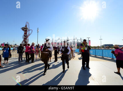 Gli ufficiali di polizia osservano l'arrivo della folla per una prova di cerimonia di apertura al Parco Olimpico di Londra. Foto Stock