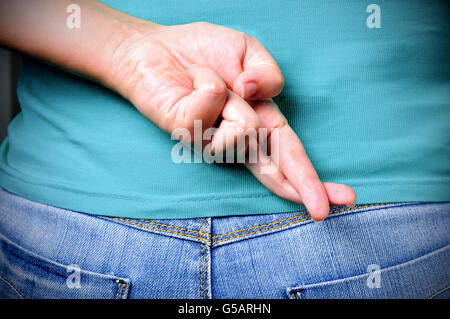 In prossimità delle dita incrociate dietro una donna di back Foto Stock