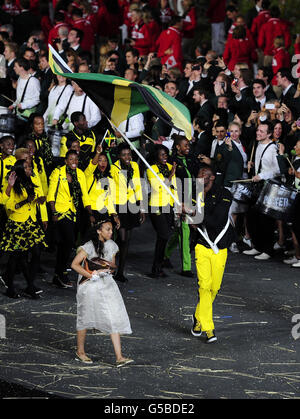 Usain Bolt della Giamaica porta la loro bandiera durante la cerimonia di apertura dei Giochi Olimpici 2012 allo Stadio Olimpico di Londra. Foto Stock