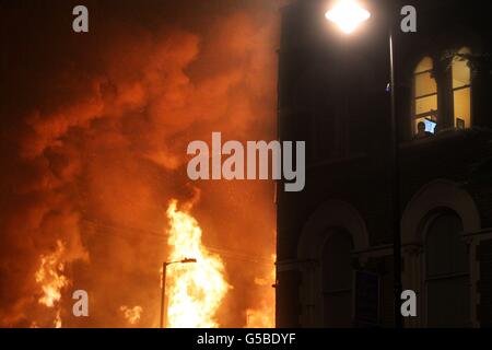 Foto inedita datata 07/08/11 dei tumulti estivi. Un uomo guarda fuori dalla sua finestra su Tottenham High Street come fiamme ingolfano l'edificio accanto, la sua televisione mostra una trasmissione della polizia circa la rivolta. Foto Stock