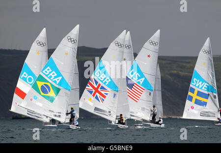 La Gran Bretagna Iain Percy e Andrew Simpson (al centro) si affiancano alla coppia brasiliana di Robert Scheidt e Bruno Prada durante la Men's Star Medal Race a Weymouth. Foto Stock