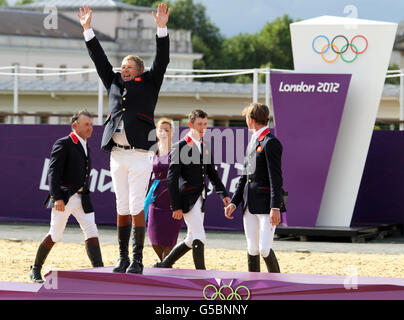 Nick Skelton della Gran Bretagna salta presto sul podio per celebrare la medaglia d'oro dopo il salto della squadra equestre, durante il giorno 10 delle Olimpiadi di Londra del 2012. Foto Stock