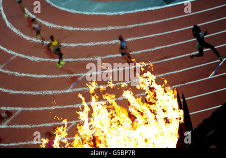 La fiamma olimpica brucia mentre gli atleti gareggiano nella semifinale femminile di 400 m Hurdles due allo Stadio Olimpico di Londra. PREMERE ASSOCIAZIONE foto. Data immagine: Lunedì 6 agosto 2012. Vedi storia della PA OLYMPICS Athletics. Il credito fotografico dovrebbe essere: Adam Davy/PA Wire. Foto Stock