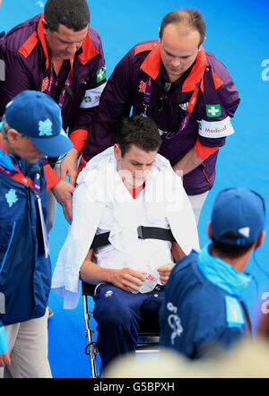 Jonathan Brownlee della Gran Bretagna viene portato via dopo il crollo al traguardo dopo il Triathlon degli uomini il giorno undici dei Giochi Olimpici di Londra ad Hyde Park, Londra. Foto Stock