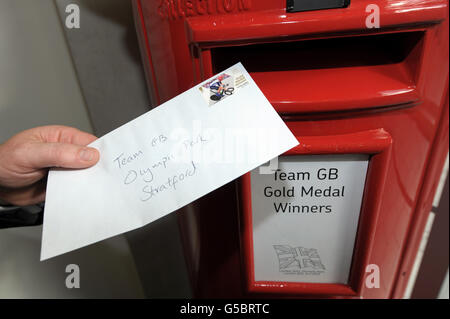 Doug Mowatt, un postino veterano, consegna una lettera con un francobollo Royal Mail che commemora il vincitore della medaglia d'oro della Gran Bretagna all'ufficio Royal Mail nel Parco Olimpico di Stratford, nella zona est di Londra. Foto Stock