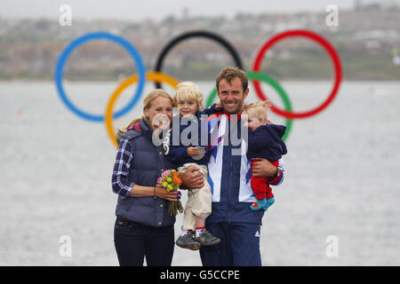 Nick Dempsey della Gran Bretagna celebra la vittoria dell'argento con sua moglie Sarah e i suoi figli, Thomas (a sinistra) e Oscar (a destra), durante la cerimonia di vittoria della RS-X Medal Race di Weymouth. Foto Stock