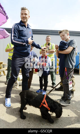 David Beckham e i suoi figli (da sinistra a destra) Romeo, Cruz e Brooklyn incontrano un cane da cecchino della sicurezza, incontrando le persone che rendono sicuri i giochi olimpici, all'interno della zona di sicurezza a Stratford East London. Foto Stock