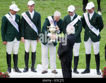 Il presidente Michael D Higgins presenta Irelands Chef d'Equipe Robert Splaine la coppa delle nazioni del FEI mentre si guarda sopra sono (da sinistra a destra) Darragh Kerins, Richie Maloney, Cian o'Connor e Clem McMahon durante il Dublin Horse Show al RDS, Dublino. Foto Stock