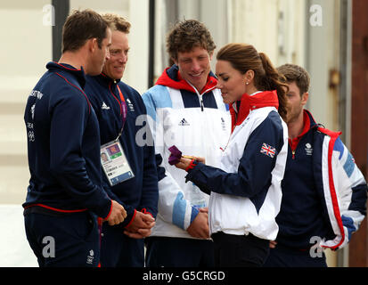 La medaglia d'oro Finn ben Ainslie della Gran Bretagna mostra la sua medaglia d'oro alla duchessa di Cambridge mentre il marinaio laser Paul Goodison e 470 marinai Stuart Bithell e Luke Patience guardano oggi alla sede della vela olimpica di Weymouth. Foto Stock