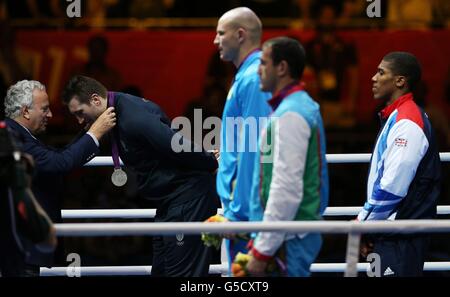 Anthony Joshua (a destra) della Gran Bretagna guarda mentre la medaglia d'argento viene assegnata a Roberto Cammarelle in Italia nella cerimonia di vittoria maschile Boxing Super Heavy (+91 kg) all'Excel Arena, l'ultimo giorno delle Olimpiadi di Londra 2012. Foto Stock