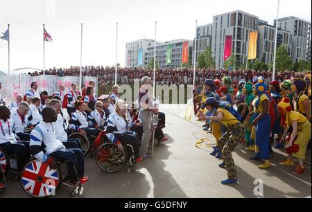 Il team Paralimpico della Gran Bretagna è accolto da un intrattenitore all'Olympic Village di Londra. Foto Stock