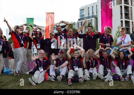 I Games Makers imitano il Usain Bolt, e il celebrativo Mo Farah pone prima dell'arrivo della squadra Paralimpica della Gran Bretagna nel villaggio Paralimpico di Londra. Foto Stock