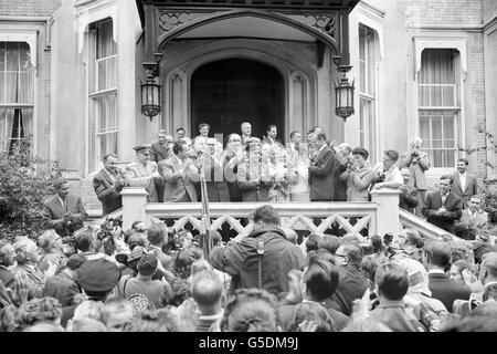 Il cosmonauta russo Yuri Gagarin applaude gli applauditori nell'ingresso imballato mentre è stato accolto al suo arrivo all'ambasciata sovietica nei giardini del palazzo di Kensington, Londra. In primo piano, sotto, i fotografi lavorano in una stampa di persone desiderose di salutare il primo uomo a viaggiare nello spazio. Major Gagarin era appena stato condotto dall'aeroporto di Londra per iniziare una visita in Gran Bretagna. Foto Stock