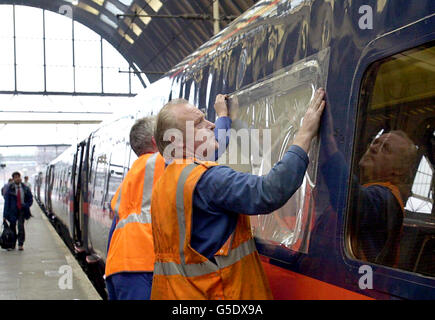 Teli di plastica temporanei sono bloccati sopra le finestre su un treno GNER, il 15.05 da Leeds a Kings Cross, alla stazione di Kings Cross a Londra. Il vetro esterno in cinque finestre è stato distrutto da pietre e mattoni gettati al treno da vandali nella zona di Wakefield. Foto Stock