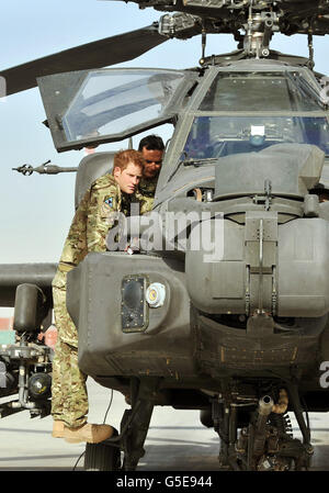 Il principe Harry esamina il cannone da 30 mm di un elicottero Apache con un membro del suo squadrone (nome non fornito) al Bastione del campo in Afghanistan, dove opererà durante il suo tour di servizio come un gunner co-pilota. Foto Stock