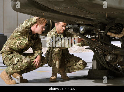 Il principe Harry esamina il cannone da 30 mm di un elicottero Apache con un membro del suo squadrone (nome non fornito) al Bastione del campo in Afghanistan, dove opererà durante il suo tour di servizio come un gunner co-pilota. Foto Stock