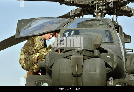 Il principe Harry esamina il cannone da 30 mm di un elicottero Apache con un membro del suo squadrone (nome non fornito) al Bastione del campo in Afghanistan, dove opererà durante il suo tour di servizio come un gunner co-pilota. Foto Stock