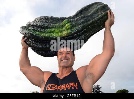 Il sollevamento pesi Jonathan Walker di Harrogate solleva un midollo del peso di 119lbs 12oz sopra la sua testa dopo che ha vinto la classe del midollo gigante nel Harrogate Autumn Flower Show, il midollo è stato coltivato da Peter Glazebrook di Newark che ha preso sei premi del primo premio nelle classi di verdure giganti allo spettacolo. Foto Stock