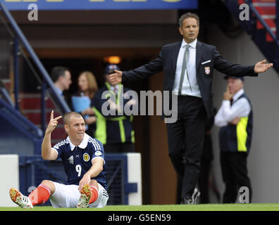Kenny Miller scozzese dopo essere stato portato giù come allenatore serbo Sinisa Mihajlovic (a destra) guarda durante la Coppa del mondo FIFA 2014 Qualifier a Hampden Park, Glasgow. Foto Stock