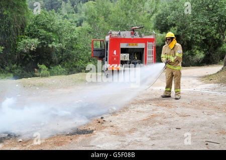 Fireman in abbigliamento protettivo si spegne un incendio come parte di una lotta antincendio drill Foto Stock