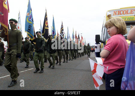 Una giovane ragazza guarda UFF mascherato (Ulster Freedom Fighters) uomini che marciano sulla Shankill Road per pagare il loro rispetto a Jackie Coulter della UFF. Coulter è stato ucciso l'anno scorso in un feudo Loyalist tra la UVF (Ulster Volonteer Force) e l'UFF. * migliaia di tifosi hanno marciato intorno all'area Shankill di Belfast prima di porre le corone al murale. Foto Stock