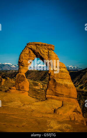 Catena montuosa innevata sullo sfondo sotto un arco nel Parco Nazionale Arches nello splendido Utah, in primavera. Natura mozzafiato e area turistica Foto Stock