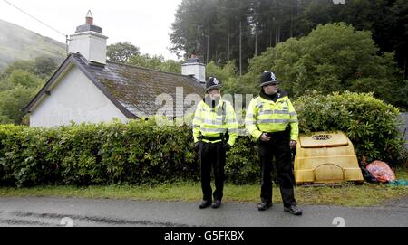 Gli ufficiali di polizia gallesi stanno fuori di una casa chiamata 'Monte Pleasant' nel villaggio di Ceinws, creduto essere l'ultima residenza conosciuta del Mark Bridger, il sospetto nel rapimento di aprile Jones. Foto Stock