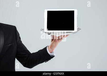 Mano del cameriere in abito nero tenendo premuto lo schermo è vuoto tablet sul vassoio Foto Stock