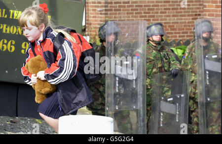 Una giovane allieva dello Schol primario delle ragazze della Santa Croce a Belfast corre a casa passando un cordone di sicurezza dell'esercito britannico dopo che lei e altri allievi e genitori sono stati scortati a casa dalla scuola attraverso la zona protestante di Ardoyne, nel nord di Belfast. Foto Stock