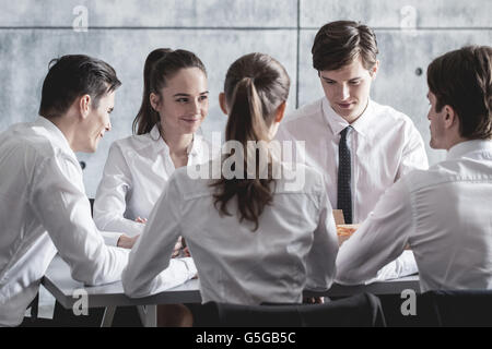 Il team Aziende di mangiare la pizza in ufficio seduti attorno al tavolo Foto Stock