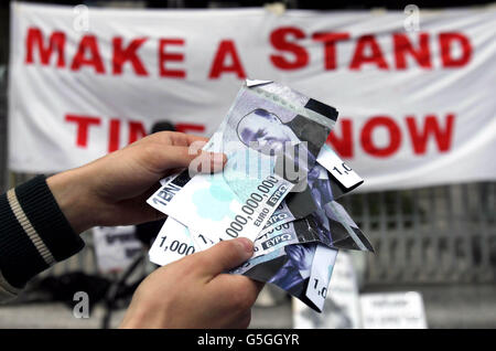 Un manifestante consegna banconote false con il ministro delle Finanze Michael Noonan durante una manifestazione fuori dalla Banca Centrale a Dublino, per segnare un anno dall'inizio dell'accampamento di Occupy Dame Street. Foto Stock