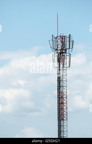 La parte superiore del telefono cellulare torre di comunicazione con più antenne e pannelli solari che la fornitura di energia elettrica contro il cielo blu Foto Stock