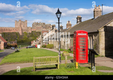 Regno Unito Inghilterra Northumberland, Bamburgh village, casella Telefono su Front Street con il castello al di là Foto Stock